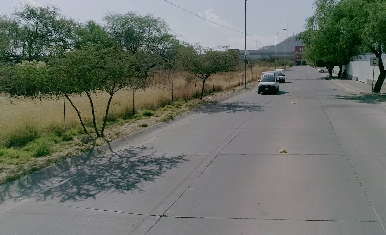 Camionetas de Ozetta en ruta a un servicio por una avenida arbolada de León, vistas desde un dron