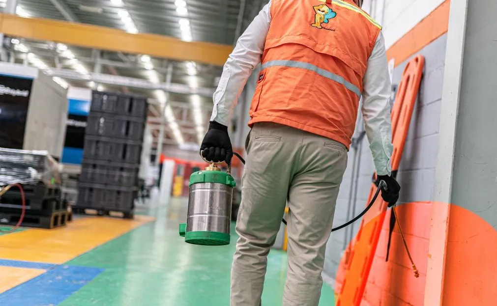 Técnico de Ozetta con chaleco naranja aplicando tratamiento dentro de una nave industrial en León
