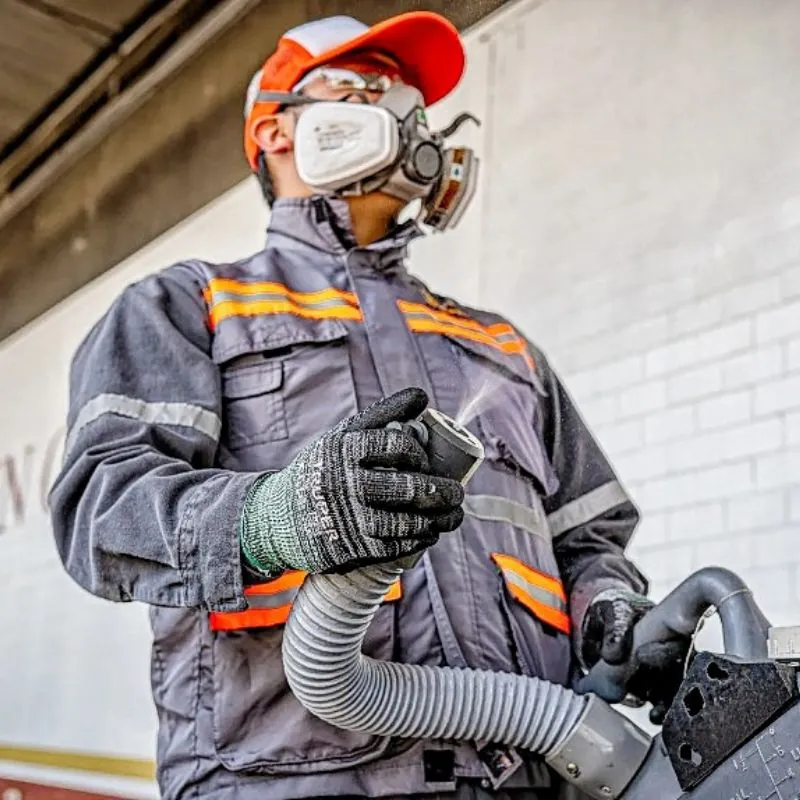 Técnico de Ozetta con gorra naranja, respirador y guantes de protección sosteniendo la manguera de aplicación antes de fumigar cucarachas en León